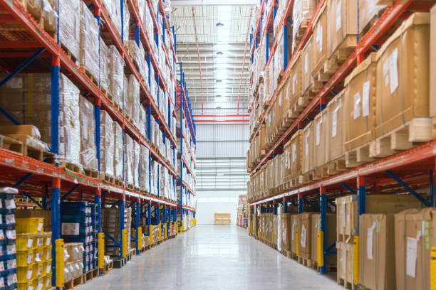 Rows of shelves with goods boxes in huge distribution warehouse at industrial storage factory